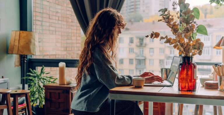Woman sitting on table working on laptop.